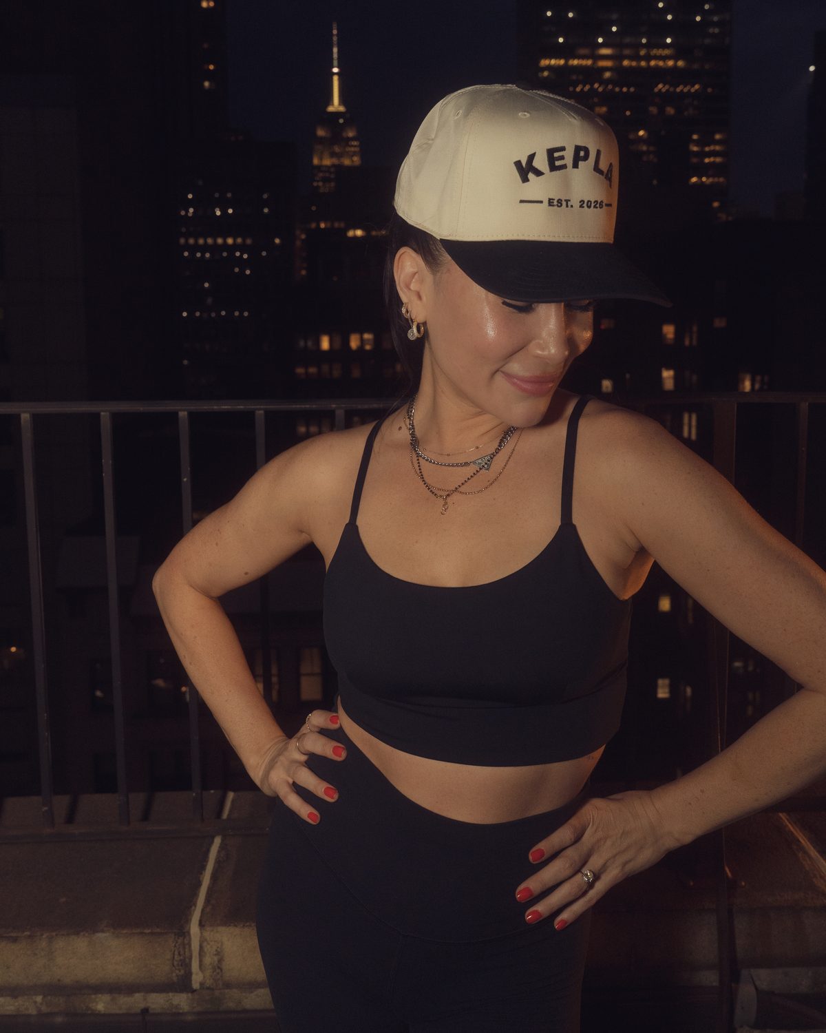 Model wearing the Kepla hat with the city glowing behind, looking down at the brim