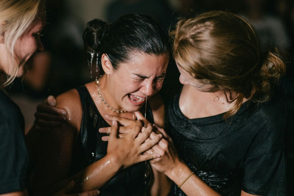 A baptism, eyes closed and hands clasped
